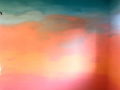 a clock tower in front of an orange and blue sky with clouds painted on it