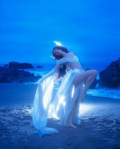 a woman in white dress sitting on the beach