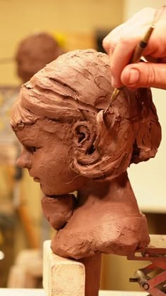 a person is working on a clay sculpture with chocolate icing in the shape of a woman's head