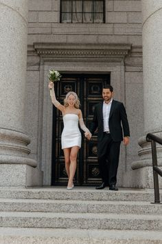 a man and woman are walking down the steps holding their hands up to each other