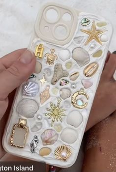 someone is holding their phone case with shells and seashells on it