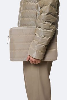 a woman wearing a jacket and pants with a purse on her back, standing in front of a white background