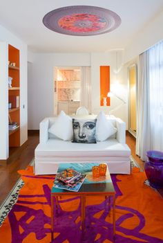 a living room with white furniture and orange accents