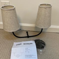 two lamps sitting next to each other on the floor near a manual for wiring them