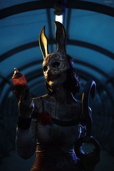 a woman dressed as a rabbit holding a bottle in her hand and wearing an evil mask