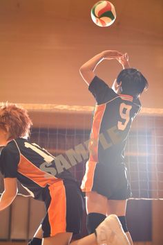 two young men playing volleyball in an indoor court