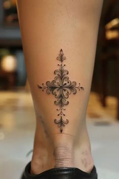 a woman's foot with a cross tattoo on the side of her leg,