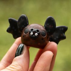 a hand holding a small black and brown toy bat with white dots on it's wings