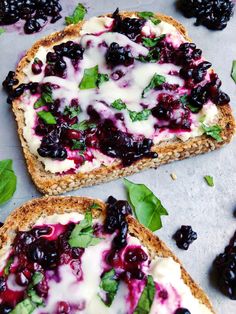 two pieces of bread with blueberries and cheese on them, next to some leaves