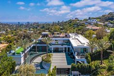 an aerial view of a modern home surrounded by trees and greenery in the foreground