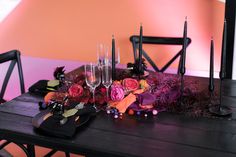 the table is set with candles, flowers and wine glasses for halloween dinner guests to enjoy