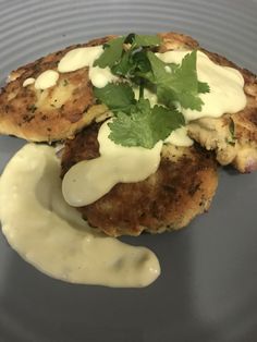 two crab cakes on a plate with sauce and parsley sprinkled on top