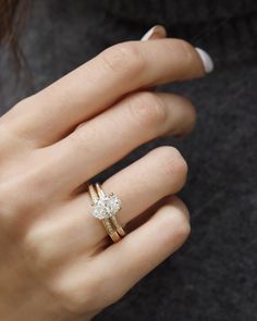 a woman's hand with a diamond ring on her left and the other hand holding an engagement ring