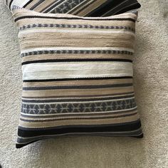 two black and white striped pillows sitting on top of a carpeted floor next to each other