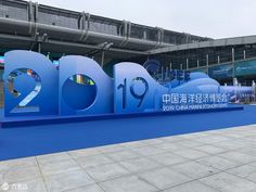 a large blue sign sitting in front of a building on top of a cement floor