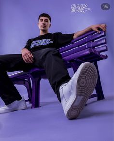 a man sitting on a purple bench with his legs crossed and one foot propped up