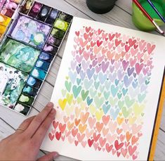 someone is painting hearts with watercolors on paper