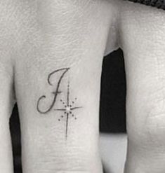 two fingers with tattoos on them, one has a cross and the other has a letter f