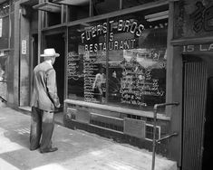 a man standing in front of a restaurant with menus written on the side of it