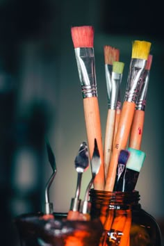 there are many brushes in the jar with spoons and paintbrushes on it