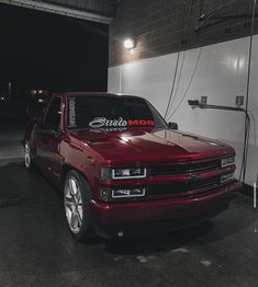 a red truck parked in front of a white wall