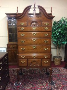 an old dresser with many drawers and knobs on it's sides, in front of a potted plant