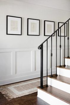 a staircase with pictures hanging on the wall and carpeted flooring in front of it