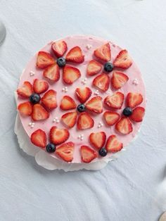 a cake with strawberries and blueberries on it sitting on top of a table