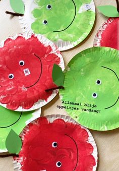 four paper plates with red apples on them and green leaves painted on the top one