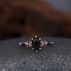 an engagement ring with black stones and rose gold accents on top of a stone surface