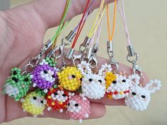 a person is holding six small key chains in their hand, each with different colored beads