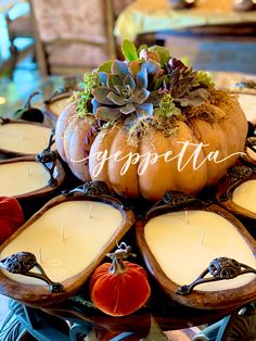 a table topped with candles and pumpkins filled with succulents on top of each other