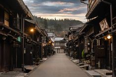 an alley way with wooden buildings on both sides and street lights at the end in between