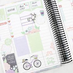 an open planner book with stickers on it and a bicycle in the middle, sitting on a table