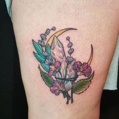 a woman's thigh with flowers and a crescent tattoo on her left side calf