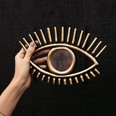 a woman's hand holding a gold eye shaped mirror