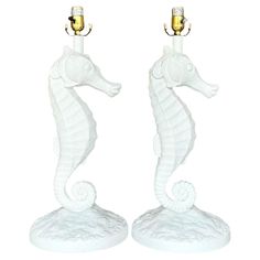 two white ceramic seahorse lamps with gold accents