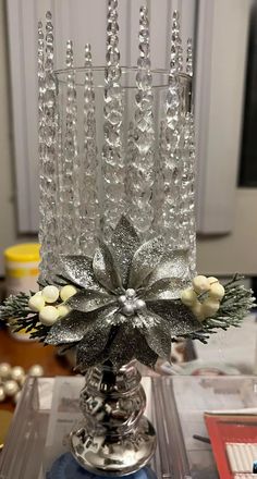 a silver candle holder with flowers and beads on it's sides, sitting on a table