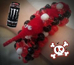 a close up of a person wearing a bracelet with beads and monster logo on it