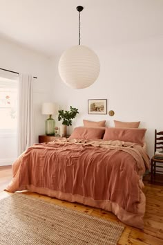 a bed sitting in a bedroom next to a window with a lamp on top of it