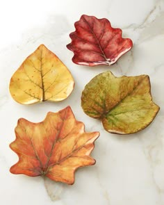 four leaf shaped dishes sitting on top of a marble counter