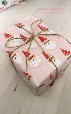 a present wrapped in pink wrapping paper and tied with twine on top of a white table