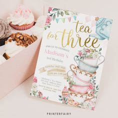 there is a box of cupcakes and a card with the words tea for three on it