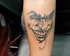 a joker tattoo on the leg of a person with an evil face and nose painted on it