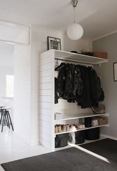 an open closet with clothes hanging on the shelves and shoes sitting on the floor in front of it