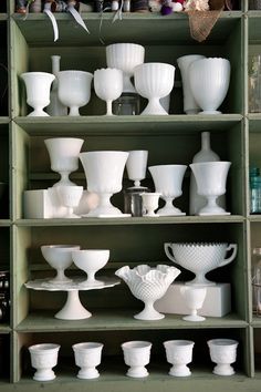 many white vases and bowls are on shelves