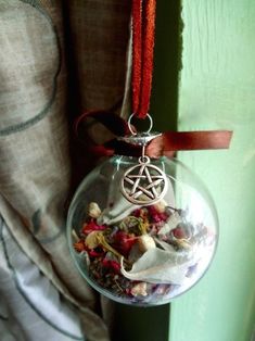 a glass ornament hanging from a red cord with a pentagramil on it