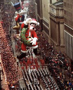 a parade float in the shape of santa claus and mickey mouse floats down a city street