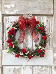 a wreath with red roses and greenery is hanging on the front door to decorate it