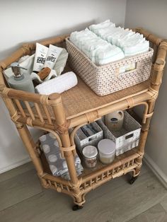 a wicker cart filled with lots of diapers and baby goods on top of a hard wood floor